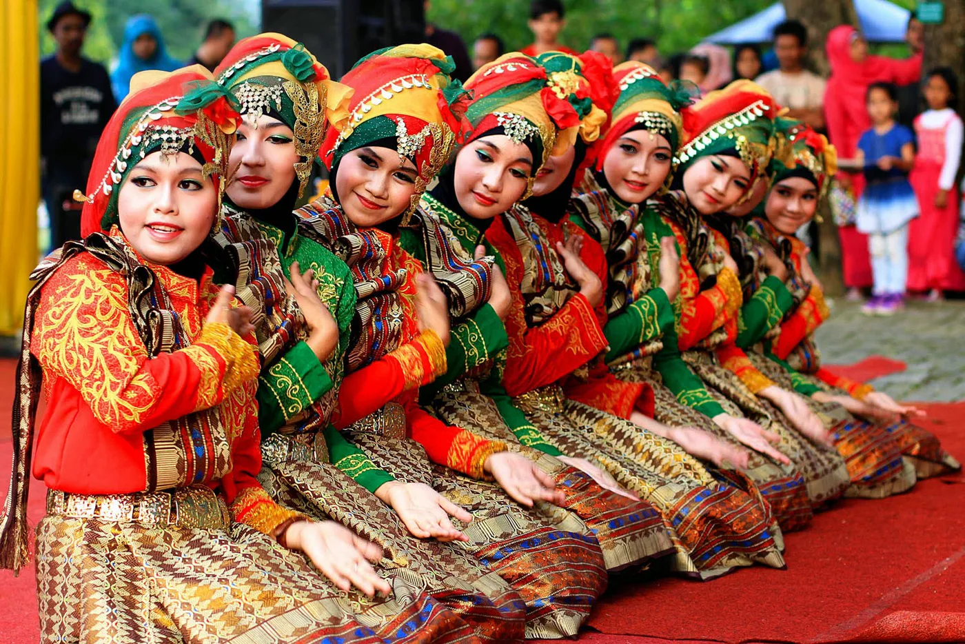 A row of young women in traditional Acehnese costume and headdresses performing a seated dance